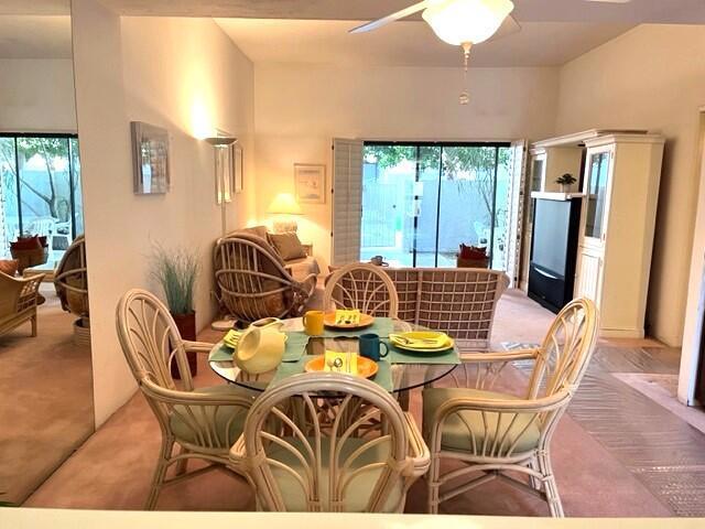 dining space featuring light carpet, ceiling fan, and a wealth of natural light