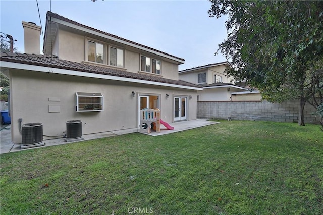 rear view of property featuring a lawn, central AC, and french doors