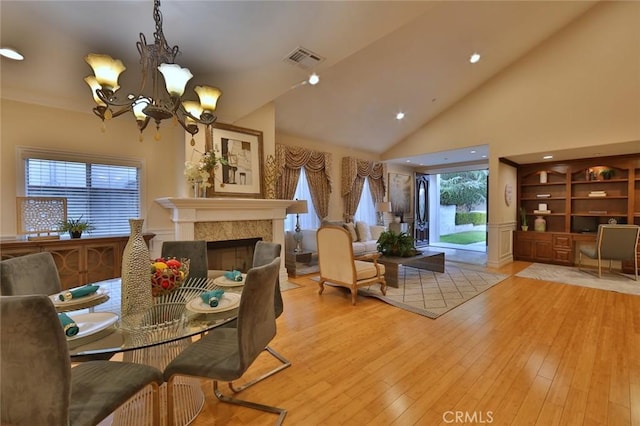 dining area with light wood-type flooring, high vaulted ceiling, and a notable chandelier