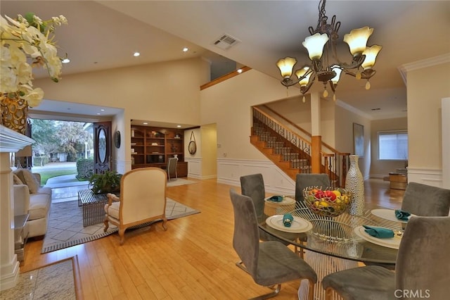 dining space with an inviting chandelier, ornamental molding, and light hardwood / wood-style flooring