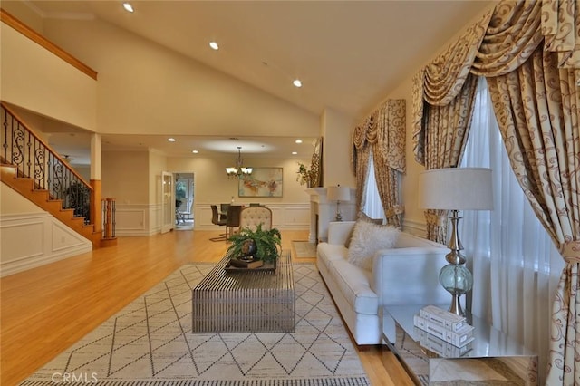 living room featuring an inviting chandelier, light hardwood / wood-style flooring, and high vaulted ceiling