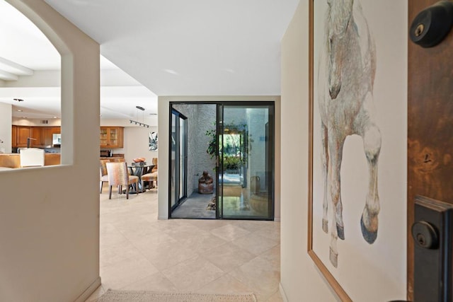 hall with floor to ceiling windows and light tile patterned flooring