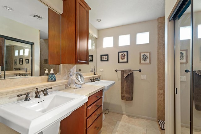 bathroom with a shower with shower door, vanity, and tile patterned floors