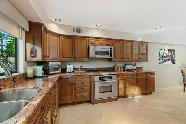 kitchen featuring light stone countertops, appliances with stainless steel finishes, and sink