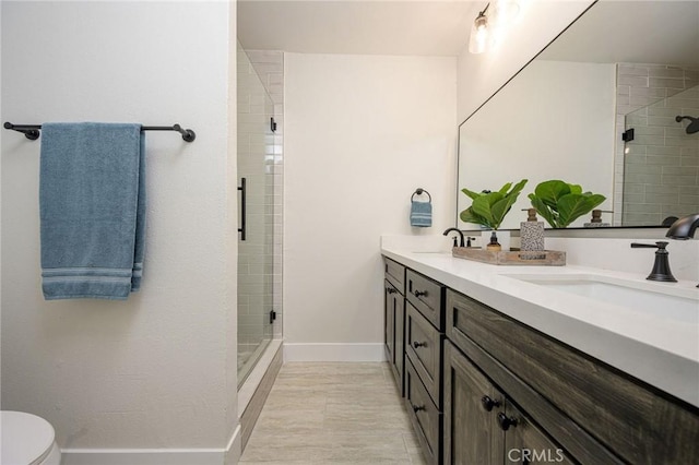 bathroom featuring toilet, vanity, and a shower with door