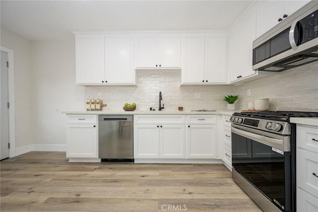 kitchen featuring appliances with stainless steel finishes, light hardwood / wood-style floors, white cabinets, and sink