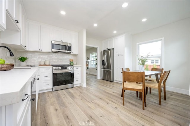 kitchen with sink, white cabinetry, a healthy amount of sunlight, light wood-type flooring, and stainless steel appliances