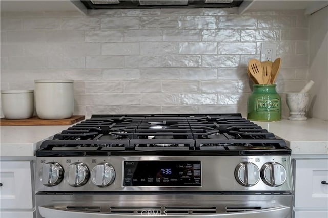 room details with decorative backsplash, stainless steel range with gas stovetop, and range hood