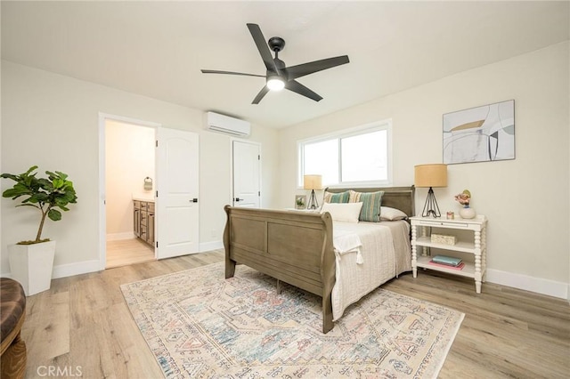 bedroom with ceiling fan, a wall mounted AC, connected bathroom, and light hardwood / wood-style flooring