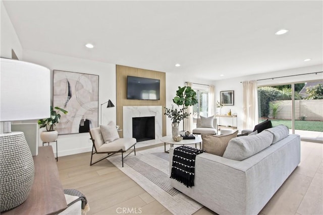 living room featuring a high end fireplace and light hardwood / wood-style flooring