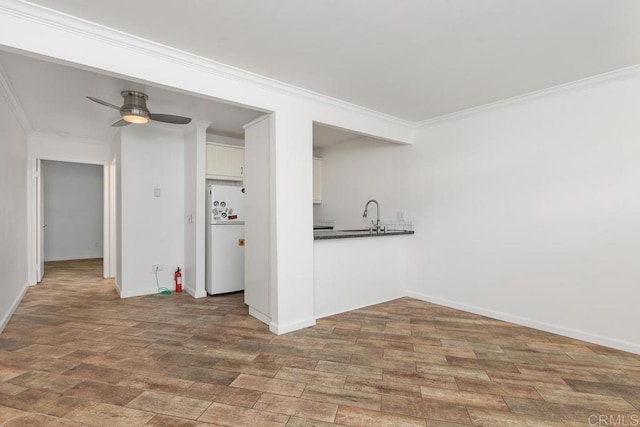 interior space featuring ceiling fan, sink, white refrigerator, and ornamental molding