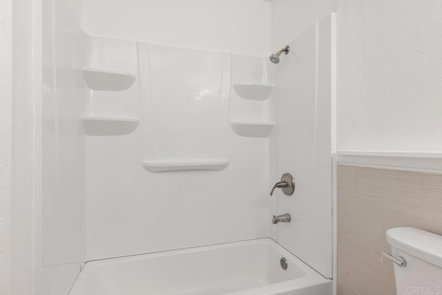 bathroom with toilet, tile walls, and bathtub / shower combination