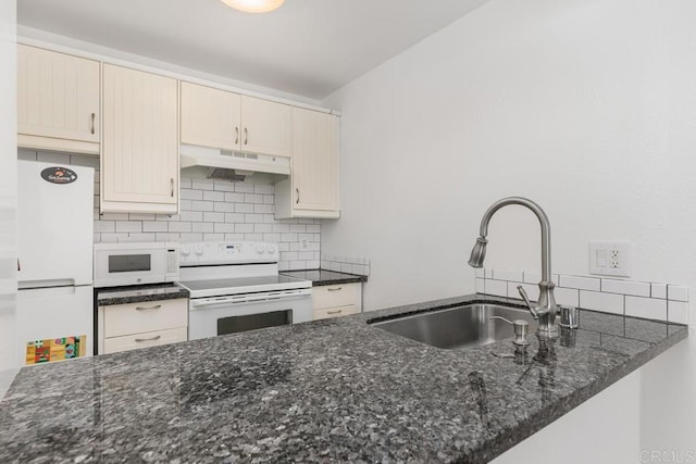 kitchen with white appliances, dark stone countertops, sink, backsplash, and kitchen peninsula