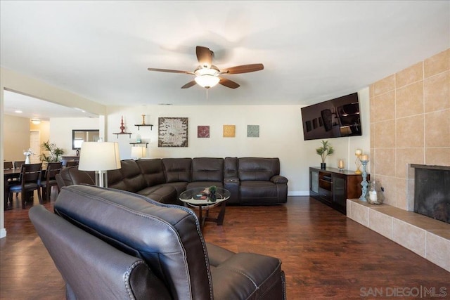 living room featuring ceiling fan, dark hardwood / wood-style flooring, and a tile fireplace