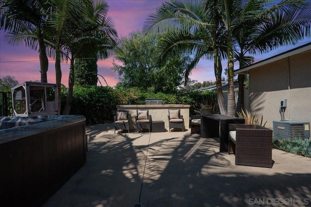 patio terrace at dusk featuring a hot tub, a bar, and central air condition unit