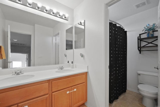 bathroom featuring toilet, tile patterned flooring, walk in shower, and vanity