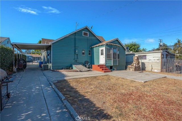 rear view of property featuring central AC unit and a carport