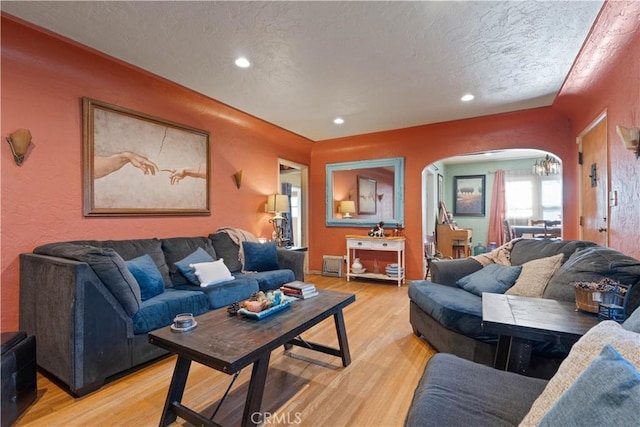 living room featuring a textured ceiling, an inviting chandelier, and light wood-type flooring