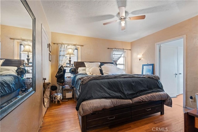 bedroom with ceiling fan, hardwood / wood-style floors, and a textured ceiling