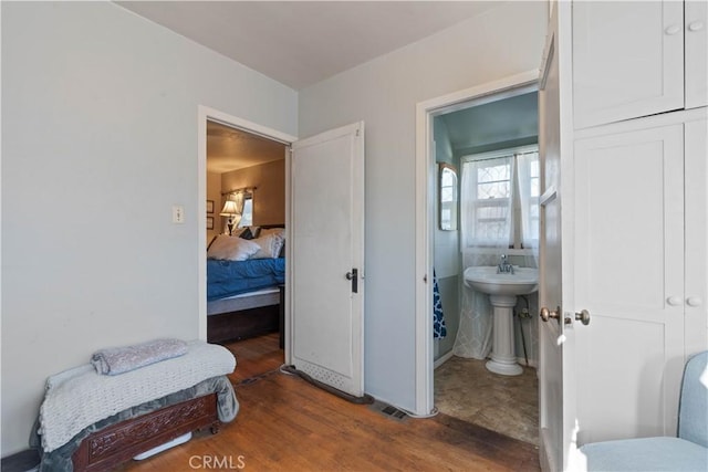 bedroom with connected bathroom and dark hardwood / wood-style flooring