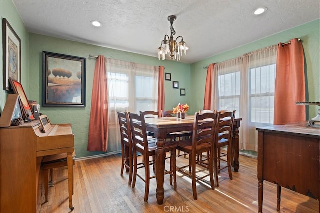 dining space featuring a textured ceiling, a chandelier, and light hardwood / wood-style flooring