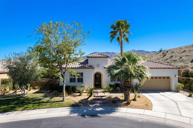 mediterranean / spanish home featuring a garage, a mountain view, and a front yard