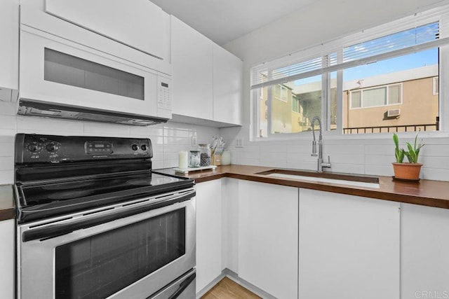 kitchen with wood counters, white cabinetry, black electric range oven, and sink