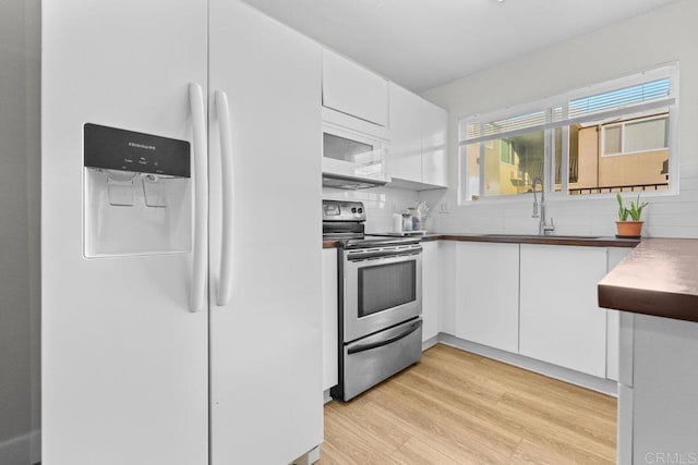 kitchen with white cabinetry, decorative backsplash, white appliances, light hardwood / wood-style flooring, and sink