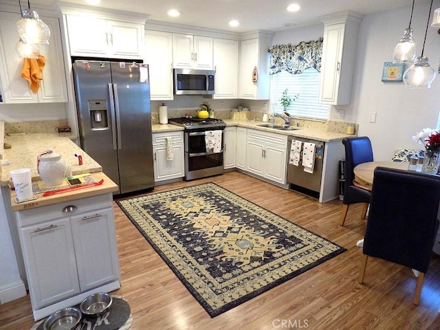 kitchen with appliances with stainless steel finishes, white cabinets, and hanging light fixtures