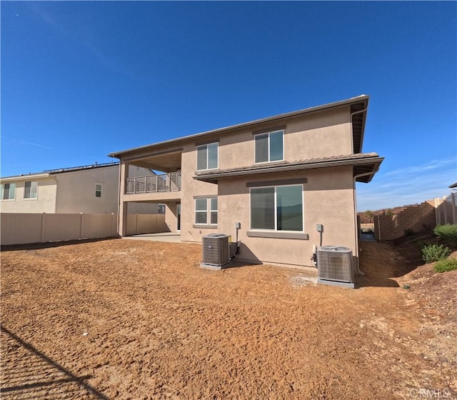 rear view of property with central air condition unit and a balcony