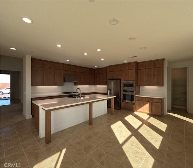 kitchen featuring appliances with stainless steel finishes, tile patterned flooring, a center island with sink, and sink