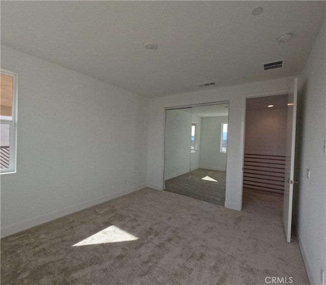 unfurnished bedroom featuring light colored carpet and a closet