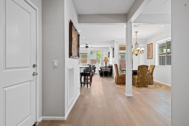 hallway with a chandelier and light hardwood / wood-style floors