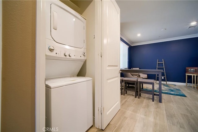 clothes washing area featuring stacked washer / dryer, light hardwood / wood-style flooring, and crown molding