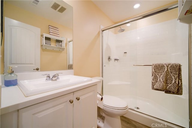 bathroom with an enclosed shower, vanity, wood-type flooring, and toilet