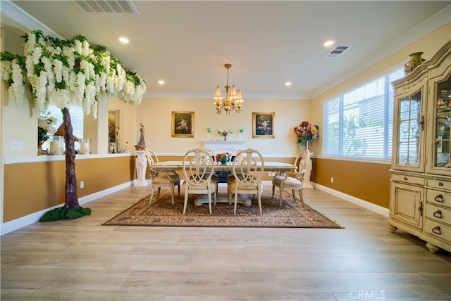 dining area featuring light wood-type flooring, a notable chandelier, and ornamental molding