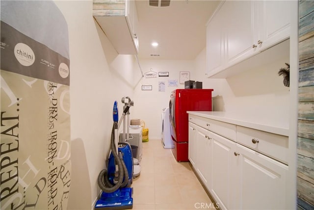 laundry area with light tile patterned flooring, cabinets, and washer and dryer