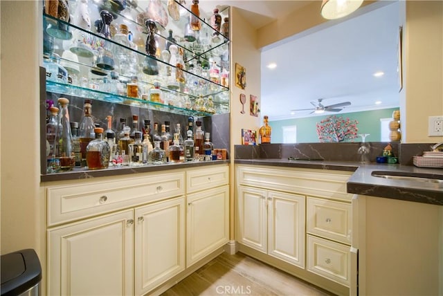 bar featuring ceiling fan, sink, and cream cabinets