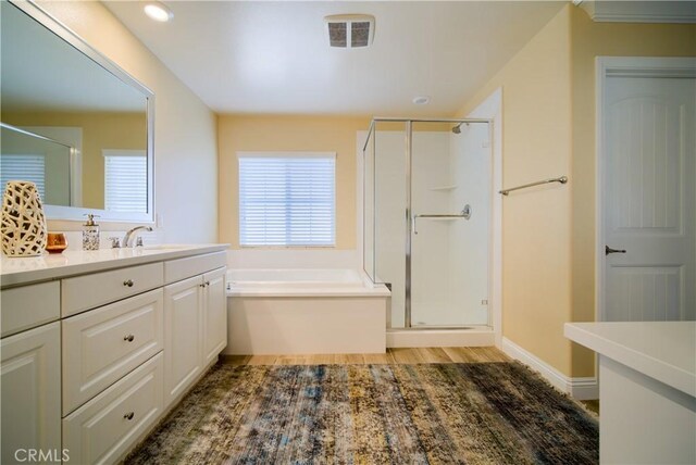 bathroom with vanity, independent shower and bath, and hardwood / wood-style floors