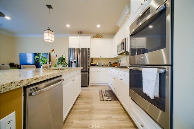 kitchen featuring white cabinetry, appliances with stainless steel finishes, hanging light fixtures, light stone countertops, and sink