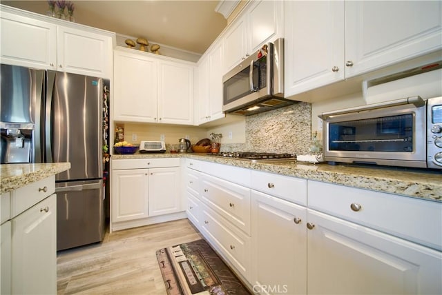 kitchen featuring tasteful backsplash, light hardwood / wood-style flooring, stainless steel appliances, white cabinets, and light stone counters