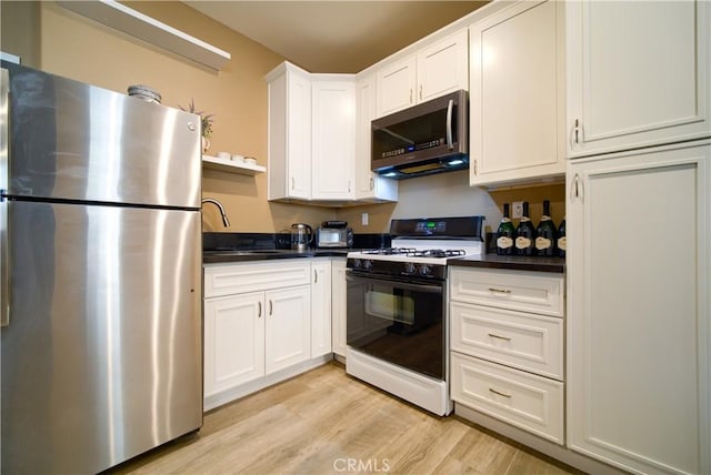 kitchen featuring white cabinets, appliances with stainless steel finishes, sink, and light hardwood / wood-style floors