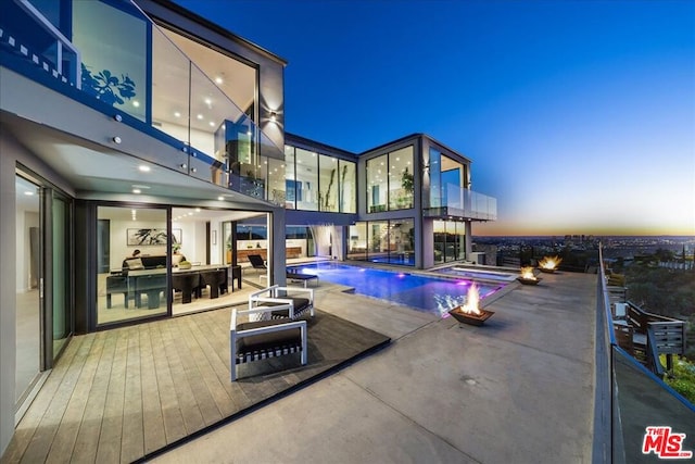 pool at dusk featuring an in ground hot tub