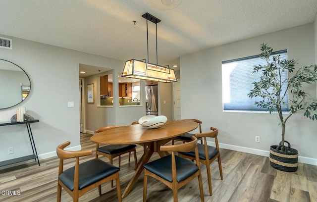 dining space with a textured ceiling and hardwood / wood-style floors