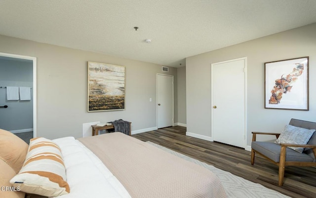 bedroom with dark wood-type flooring, connected bathroom, and a textured ceiling