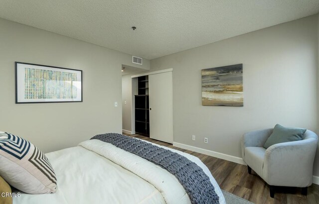 bedroom with a closet, dark hardwood / wood-style floors, and a textured ceiling