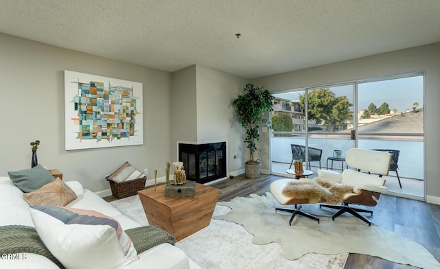 living room featuring hardwood / wood-style flooring, a multi sided fireplace, and a textured ceiling