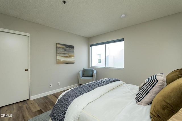 bedroom featuring a closet, dark wood-type flooring, and a textured ceiling