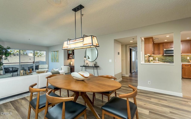 dining area with wood-type flooring and a textured ceiling