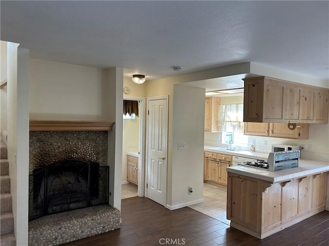 kitchen with kitchen peninsula, a breakfast bar area, dark hardwood / wood-style floors, light brown cabinetry, and sink